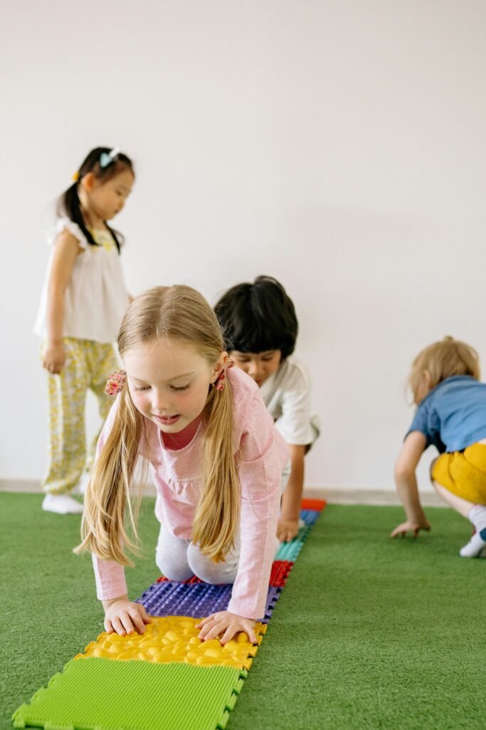 Happy children playing on colorful mats in an indoor playroom.